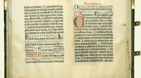 Una copia del Salterio di Magonza aperto su una doppia pagina contenente decorazioni manoscritte policrome e spartiti musicali